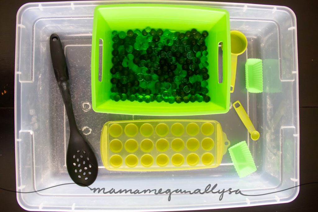 a top down shot of the sensory bin as well as the spoons and ice cube tray for play