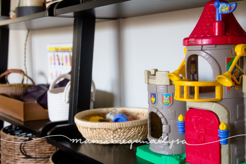 An overview of her play shelf with her Little peoples castle and other baskets of toys