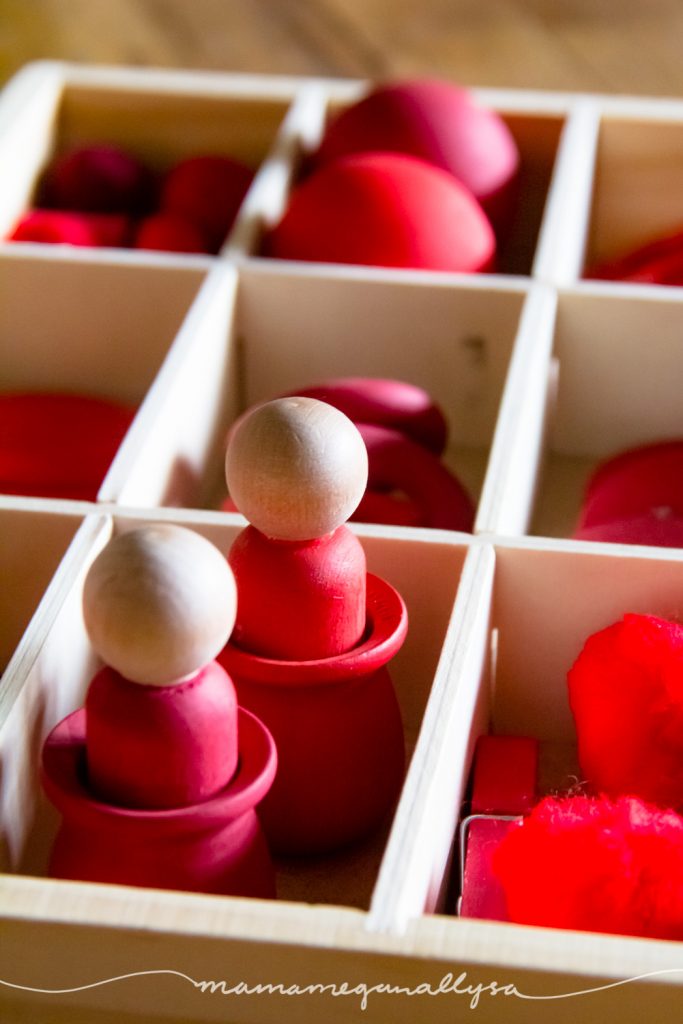 red wooden loose parts toys in a divided tray