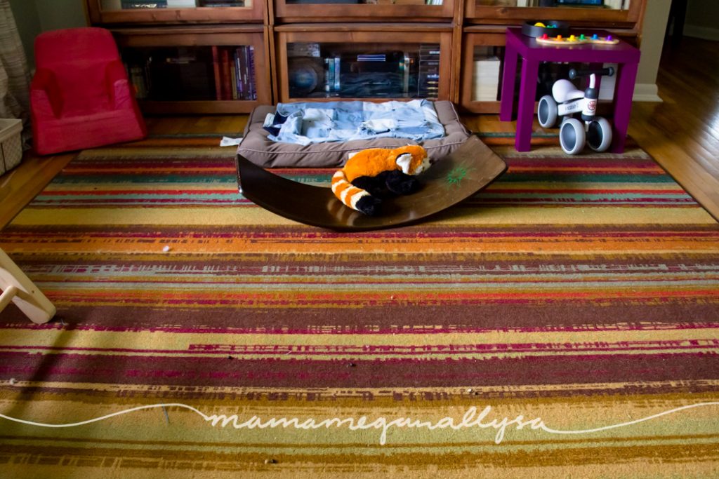 a living room play space with a wobble board small play table and baby bike