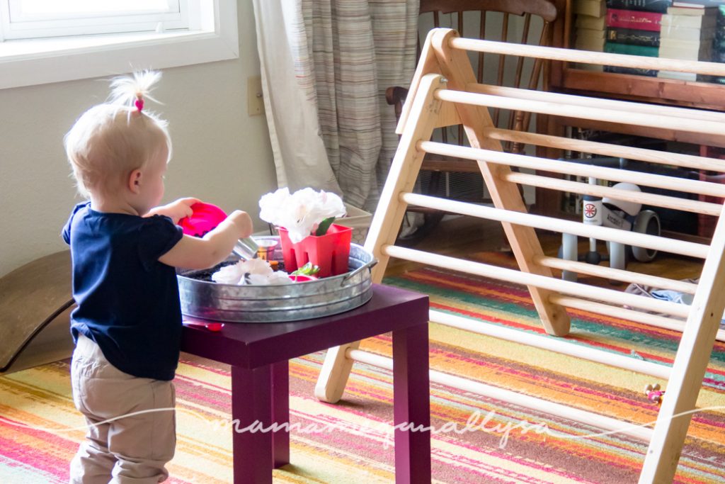 a toddler playing at a play table with a sensory bin in a living room