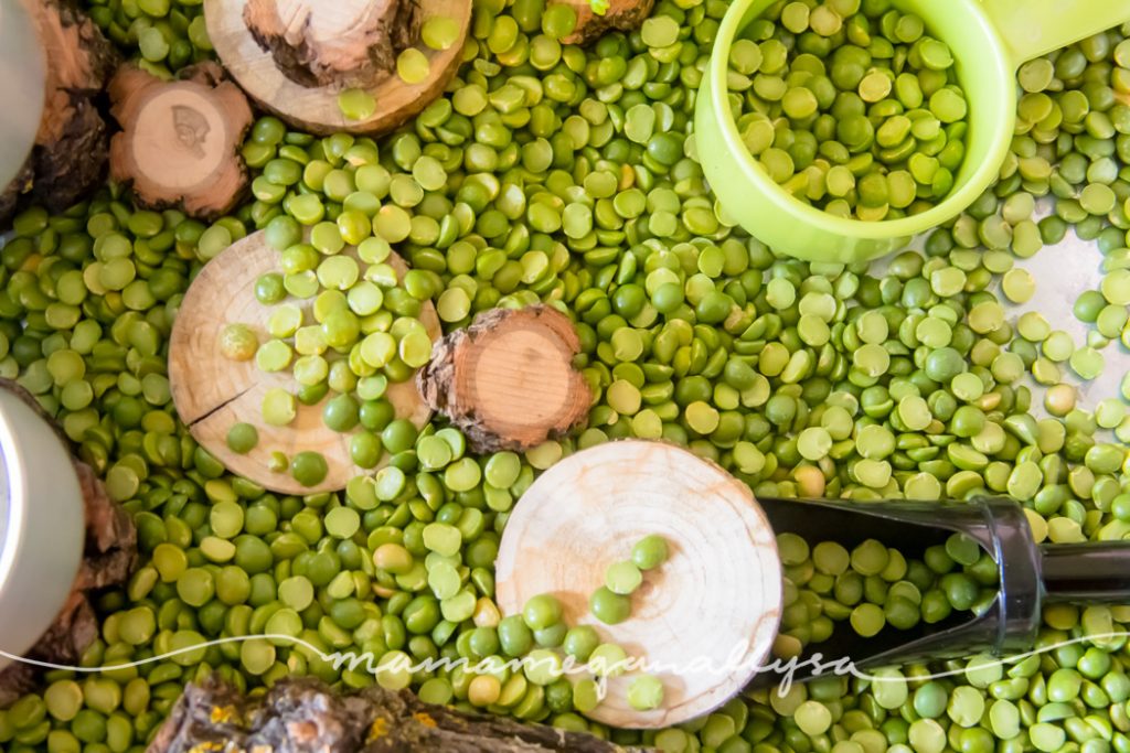 a close up of split peas with wood slices and a green measuring cup and mini scoop