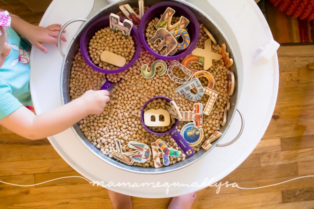 a toddler scooping in the ABC's and Chick Peas sensory bin 