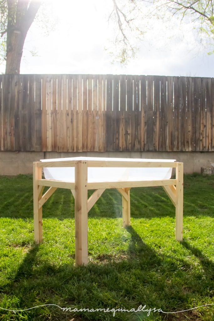 fully constructed DIY sensory bin table sitting the yard with backlit sunlight