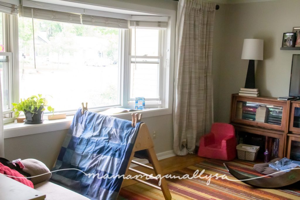 living room with large bay window with a pikler triangle and a wobbleboard as well as a toddler armchair