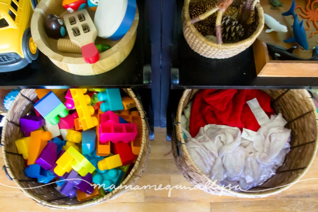 large wicker baskets filled with Megablocks and babydolls on the bottom of the play shelf