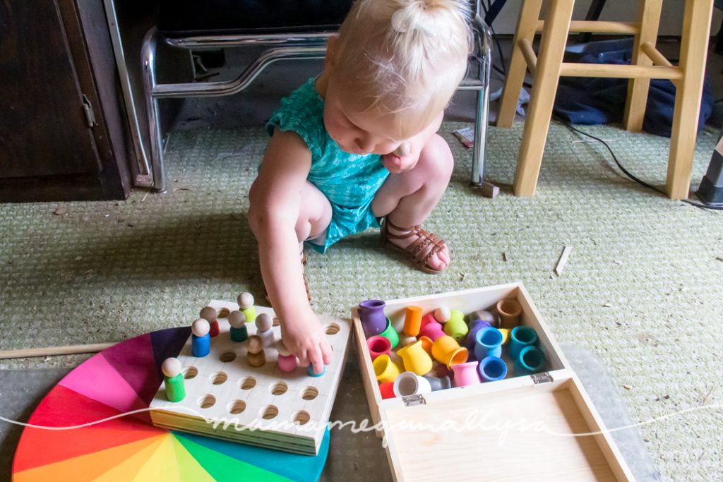 a toddler squatting down on the shop floor to play with the peg person board loose parts tool