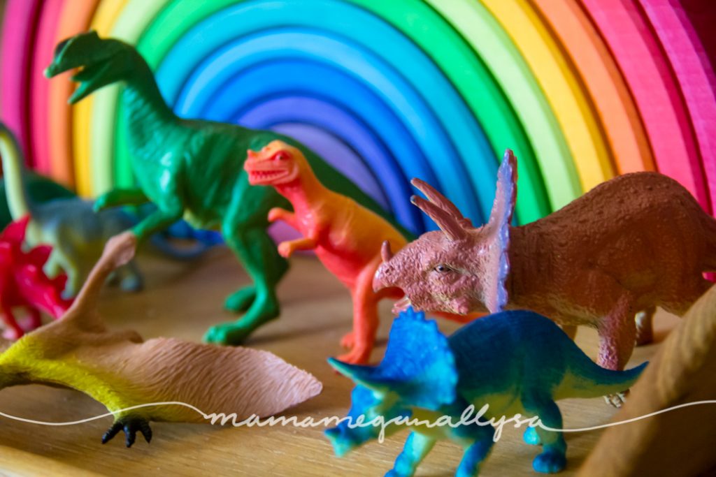 a rainbow of dinosaurs in front of a Grimms rainbow