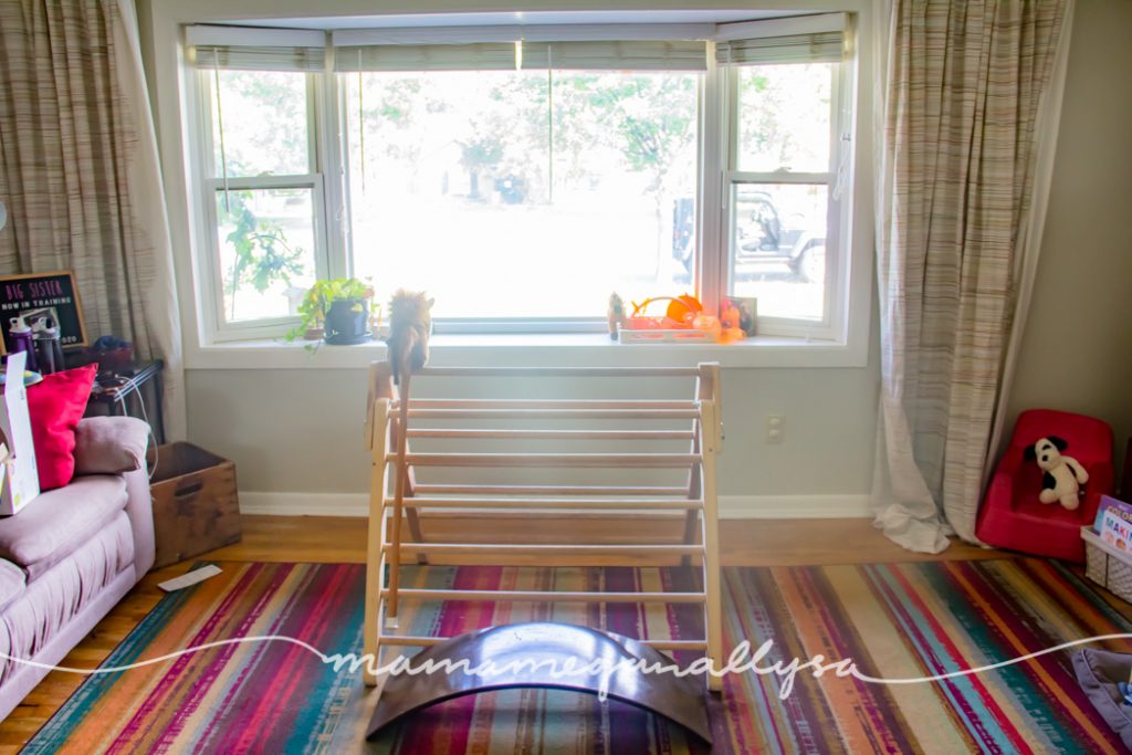 we have a Pikler triangle, wobble board, reading corner, puzzle table as well as her doll house out in the living room this month for our2-year-old toy rotation.