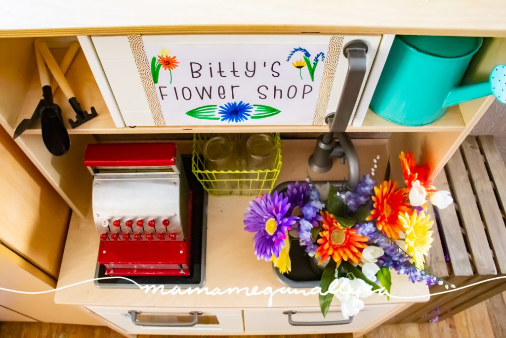 I placed a cash register on the stove side of her play kitchen, added some small jars to arrange flowers in and a bucket of flowers. As additional themed items I included a watering can and some little shovels.