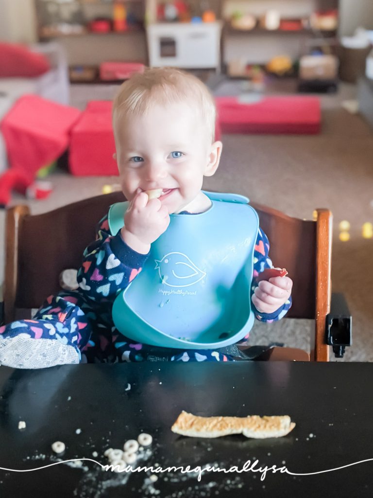 a baby eating with one foot up on the table