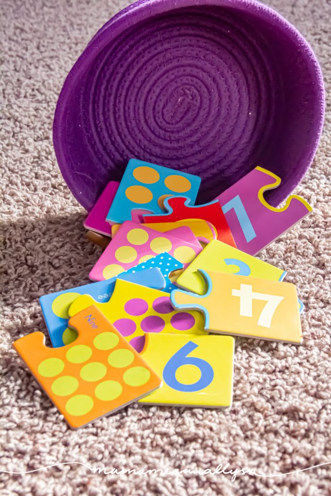 a set of 2 part jigsaw puzzles spilling out of a purple rope basket