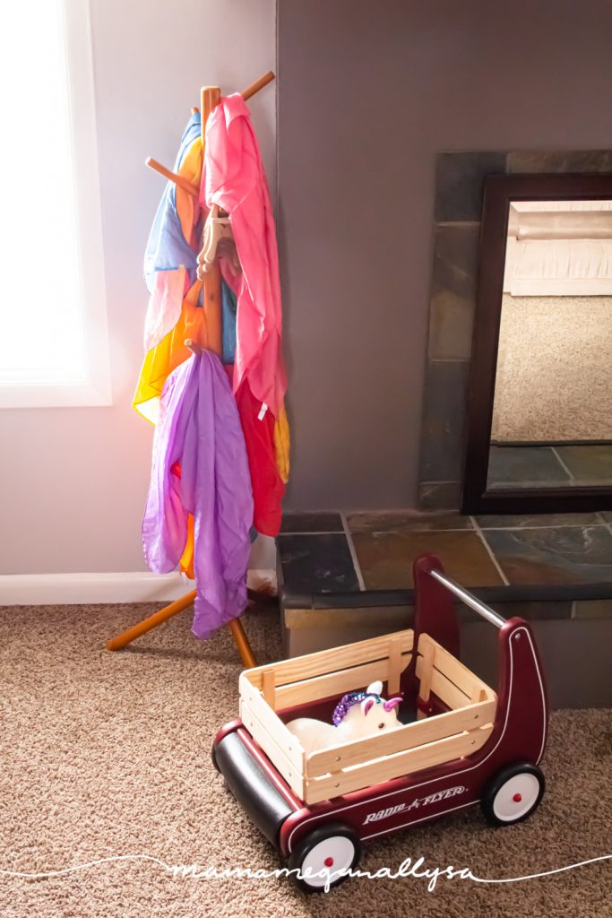 our play silks hanging on a kids coat rack with the toddlers push wagon sitting in front