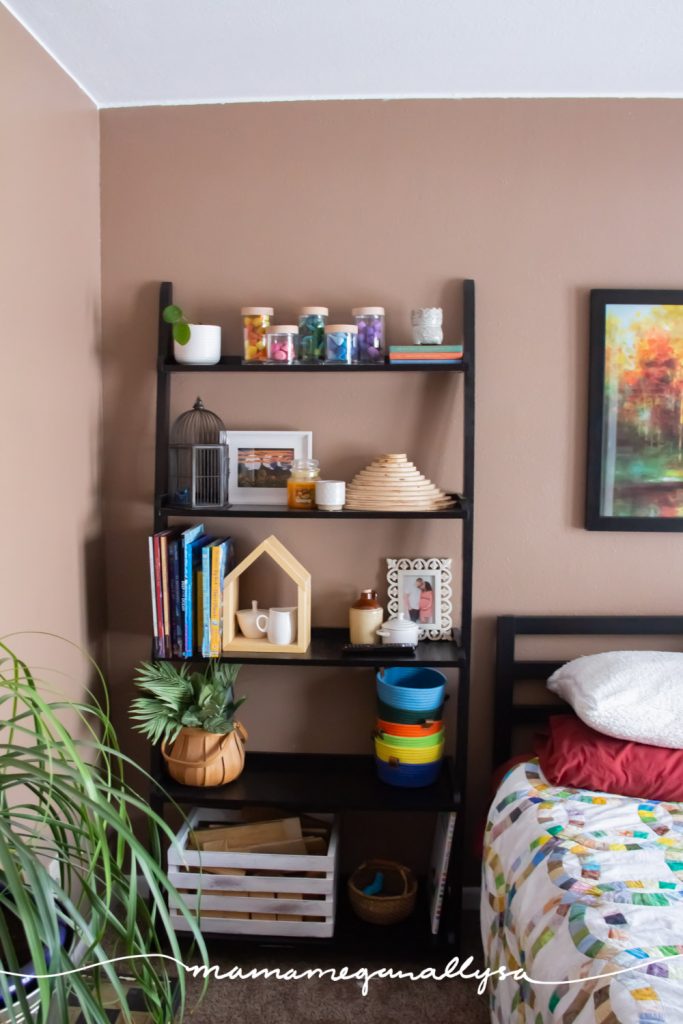 a tall black bookshelf in our guest room holding some of our loose parts, wooden blocks, books, and extra small world supplies