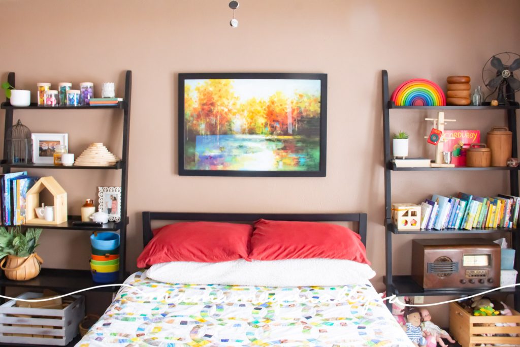 A guest room with tall bookshelves on either side of the bed with toys as well as general decor styled on the shelves