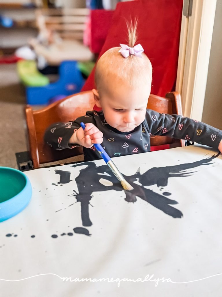 a little toddler using a caligraphy practice sheet to paint with water