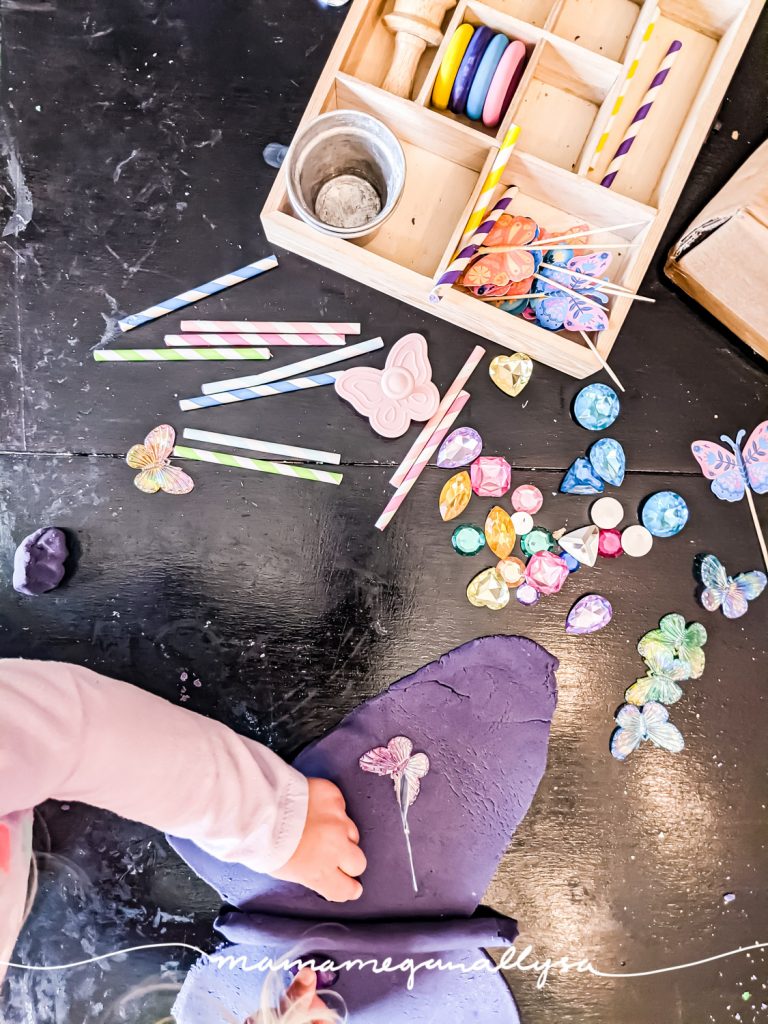 a top down shot of a child playing with a butterfly-themed play dough tray