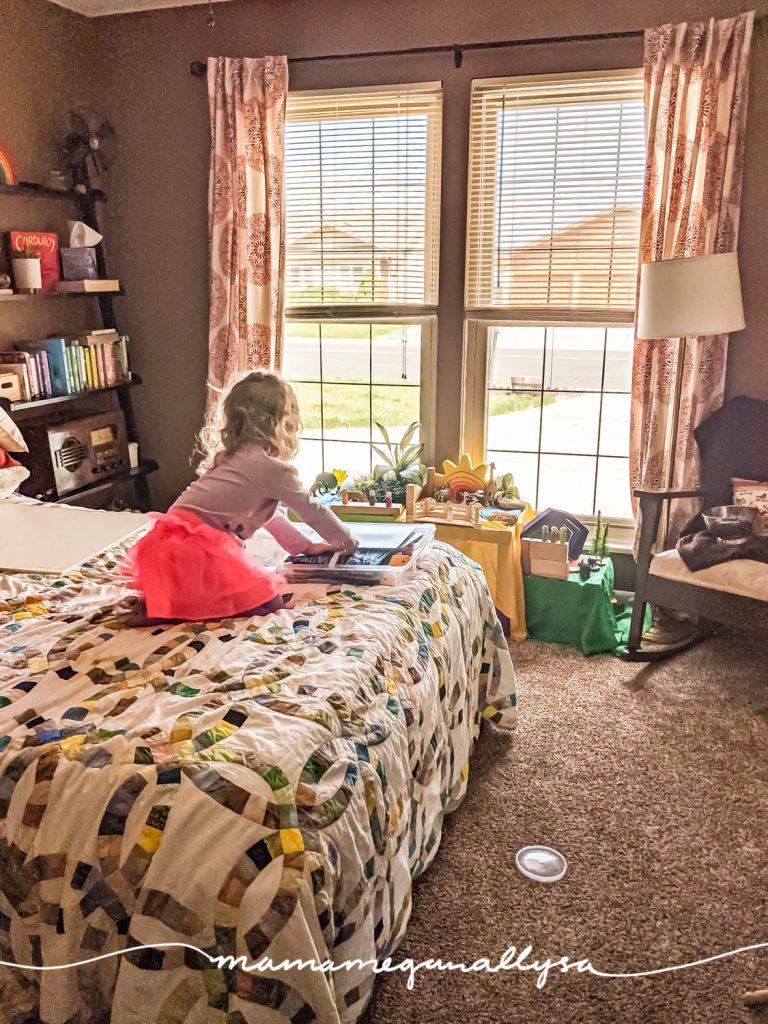 a little girl kneeling on a bed getting some toys out of a box