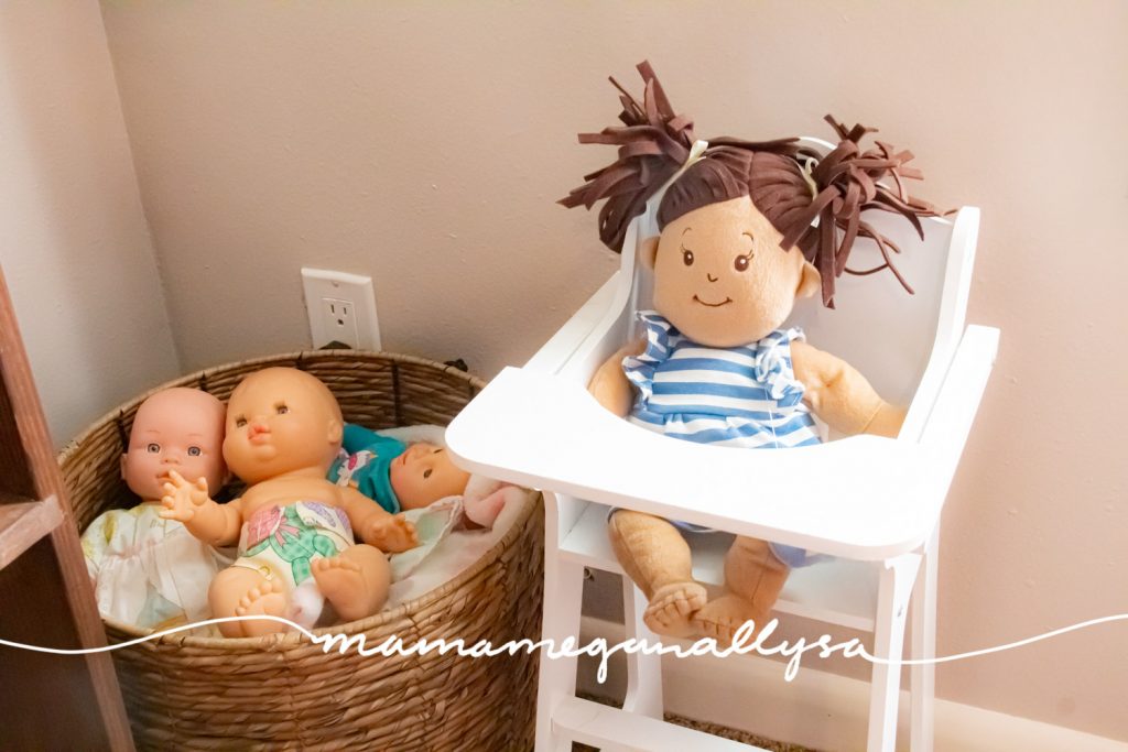 a basket full of baby dolls and a white baby doll highchair with a doll sitting in it