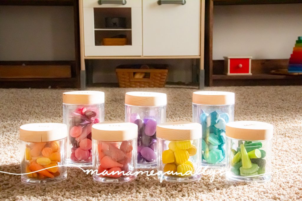 a close up of acrylic maple and lark jars filled with rainbow wooden loose parts