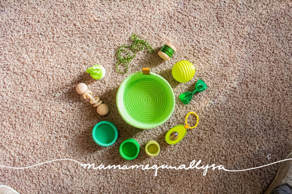 a lime green rope basket on the floor surrounded by green baby toys