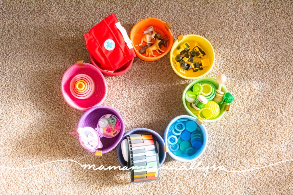 a rainbow of rope baskets filled with toys arranged as a circle on the floor