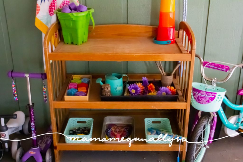 wooden diaper changing table holds baskets and trays of toys for out outdoor toy rotaion