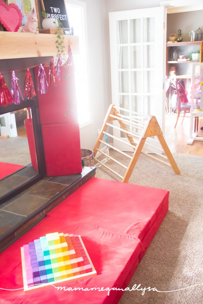 Our living room playroom has our homemade pickler triangle in the corner and our nugget play couch in the center of the room. We are currently keeping our rainbow stepped pyramid blocks on the nugget