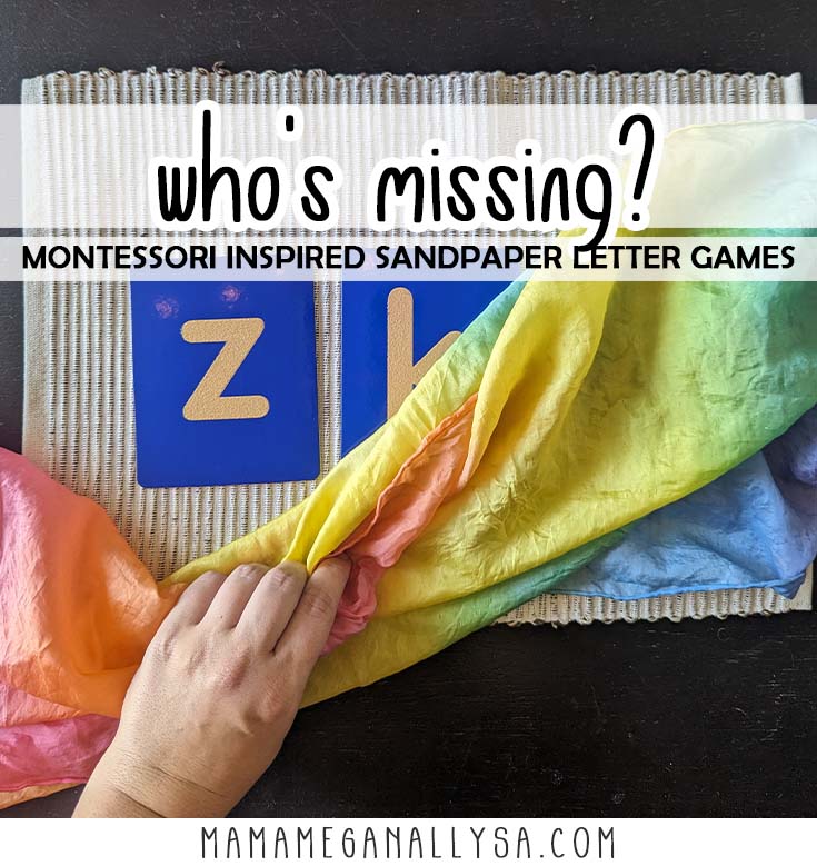a pin image that reads swho's missing  Montessori inspired sandpaper letter games overlayed a picture of a tan work mat on a black table with blue sandpaper letters on the mat. A hand is gripping a rainbow silk that is partially covering the sandpaper letters
